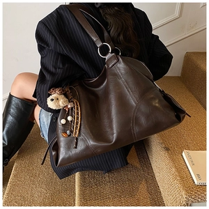 Dettaglio borsa tote marrone scuro con ciondolo a forma di orso e perline colorate