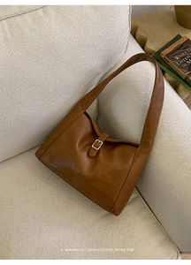 Detail of vintage brown leather tote bag showing silver buckle and fine grain texture