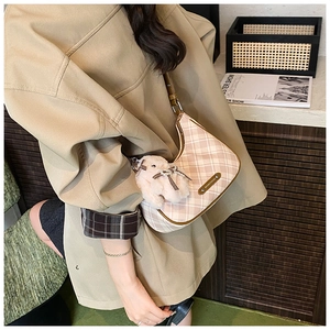 Close-up of pink checkered hobo bag with plush rabbit charm and brown leather details