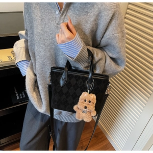 Détail d'un sac cabas noir matelassé avec charme de chien en peluche et bandoulière