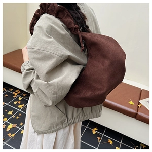 Detail of dark brown suede crescent bag featuring distinctive pleated shoulder strap design