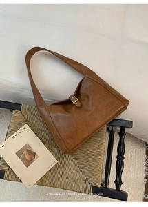 Close-up of brown PU leather tote bag featuring a silver square metal buckle and texture