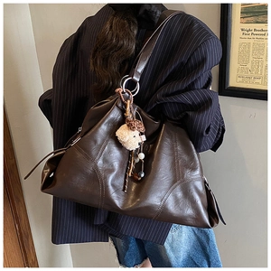 Vista dettagliata della borsa tote in pelle vintage caffè con ciondolo a orsetto