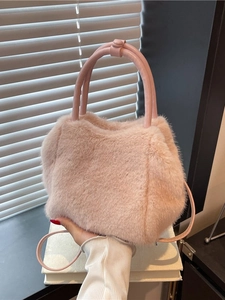Chic pink faux fur handbag with soft texture and detachable shoulder strap on white books