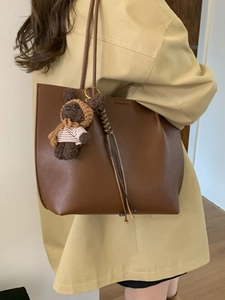 Brown leather tote bag with cute crochet bear charm shown on a female model shoulder