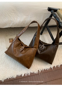 Detailed view of brown leather tote bags with metal buckles on a cozy textile background