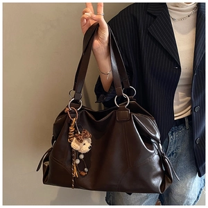 Dettaglio borsa tote in pelle marrone scuro con orsetto di peluche e fiocco leopardato