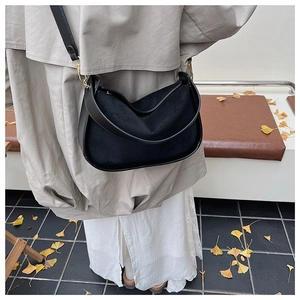 Détail d'un sac hobo noir rétro en daim avec une bandoulière réglable et élégante