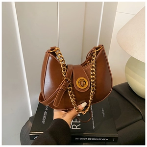Dettaglio di una borsa hobo a mezzaluna marrone con catena dorata e chiusura a scatto