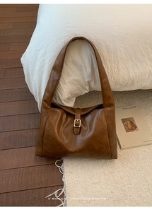 Detailed close-up of retro brown tote bag with silver buckle on a cozy rug background