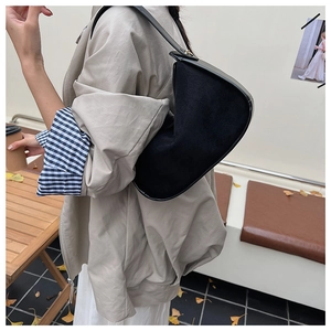 Détail du sac hobo en daim noir porté avec une tenue d'automne en extérieur