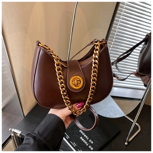 Dettaglio borsa a mezzaluna in pelle marrone con catena dorata e fibbia rotonda