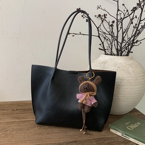 Détail du cabas noir texturé avec un charmant porte-clés ours en peluche marron
