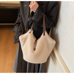 Close-up of fluffy beige plush tote bag with dark brown leather handles and silver twist lock