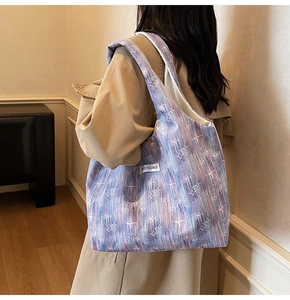 Detail of the purple star pattern tote bag featuring a 'KISS YOURSELF' woven label tag