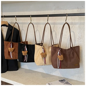Detail of four colorful suede tote bags with cute teddy bear charms and brand logo