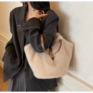 Close-up of beige plush tote bag featuring brown leather straps and silver metal swivel lock