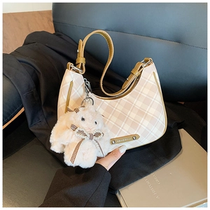 Detail of beige checkered dumpling bag with plush rabbit charm and metal logo plate