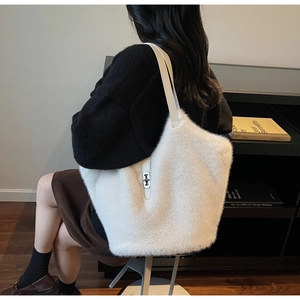 Close-up of white plush tote bag with leather straps and silver metal swivel lock