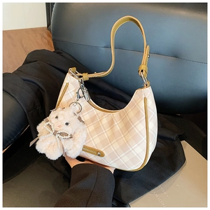 Detail of checkered hobo bag featuring brown leather trim and white plush bunny charm