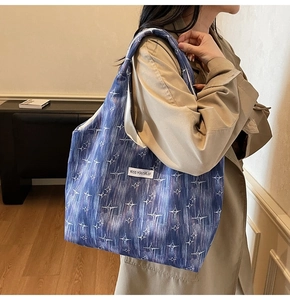 Detail view of a large blue tote bag with star patterns and KISS YOURSELF label