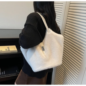 Detail of white faux fur tote bag showing the silver metal twist lock and leather strap