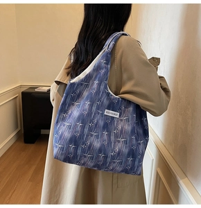 Detail view of a blue canvas tote bag with star patterns on a model's shoulder