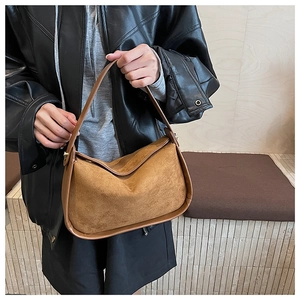 Détail d'un sac à main en daim marron avec garniture en cuir et design incurvé
