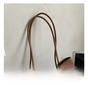 Detailed close-up of cylindrical handles on a brown suede tote bag with neat stitching