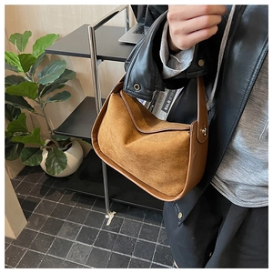 Détail du sac à main en daim marron avec textures mixtes et boucle dorée élégante