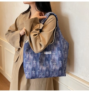 Detail of navy blue canvas tote bag with white star pattern and Kiss Yourself label