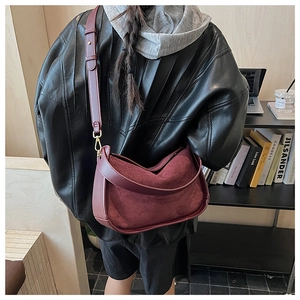 Détail du sac demi-lune en daim bordeaux montrant la chute de la bandoulière et texture
