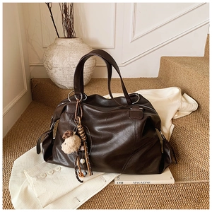 Dettaglio della borsa tote vintage in pelle marrone con ciondolo a cane e perline