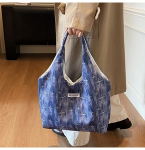 Close-up of deep blue canvas tote bag with star print and Kiss Yourself label