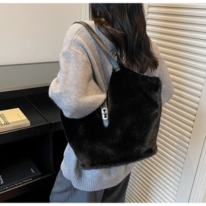 Detail of a plush black faux fur tote bag with a silver metallic clasp worn by a model