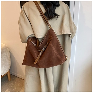 Detailed close-up of a large brown suede tote bag with leather straps and metal eyelets