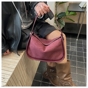 Détail de la texture en daim bordeaux d'un sac à bandoulière tendance en demi-lune
