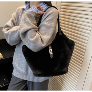 Close-up of black plush tote bag featuring leather straps and silver metal buckle detail