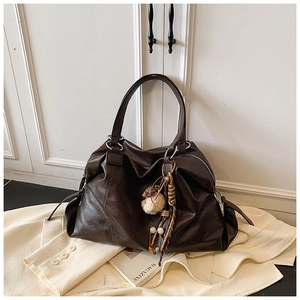 Dettaglio della borsa tote in pelle sintetica marrone scuro con ciondolo boho