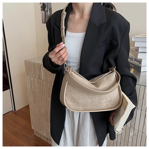 Détail d'un sac à bandoulière en similicuir beige porté avec un style décontracté