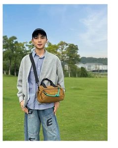 Bolso bandolera marrón con detalle de cuerda verde llevado por modelo en exteriores