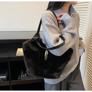 Detail of black faux fur tote bag featuring a silver metal twist lock and leather strap
