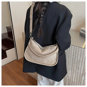 Close-up of beige suede shoulder bag featuring a half-moon design and adjustable strap