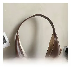 Gros plan détaillé du sac fourre-tout marron en demi-lune avec gland en perles de bois texturé