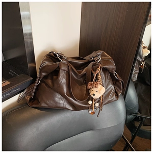 Dettaglio della grande borsa tote marrone vintage in pelle con ciondolo a forma di orso