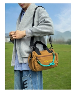 Detalle de un bolso bandolera amarillo mostaza con cuerda verde y correas negras al aire libre