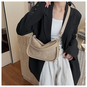 Détail d'un sac bandoulière en suédine de style dumpling avec bordures en cuir contrasté
