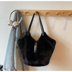 Detail of black faux fur tote bag with leather straps hanging next to a denim jacket
