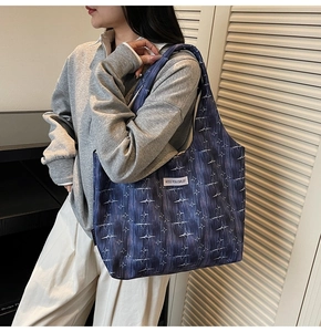 Detailed shoulder view of a large blue canvas tote bag with star patterns and logo tag