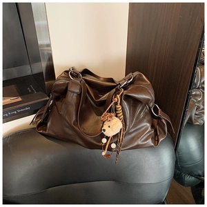 Dettaglio ravvicinato della borsa Boston vintage marrone scuro con ciondolo a orsetto